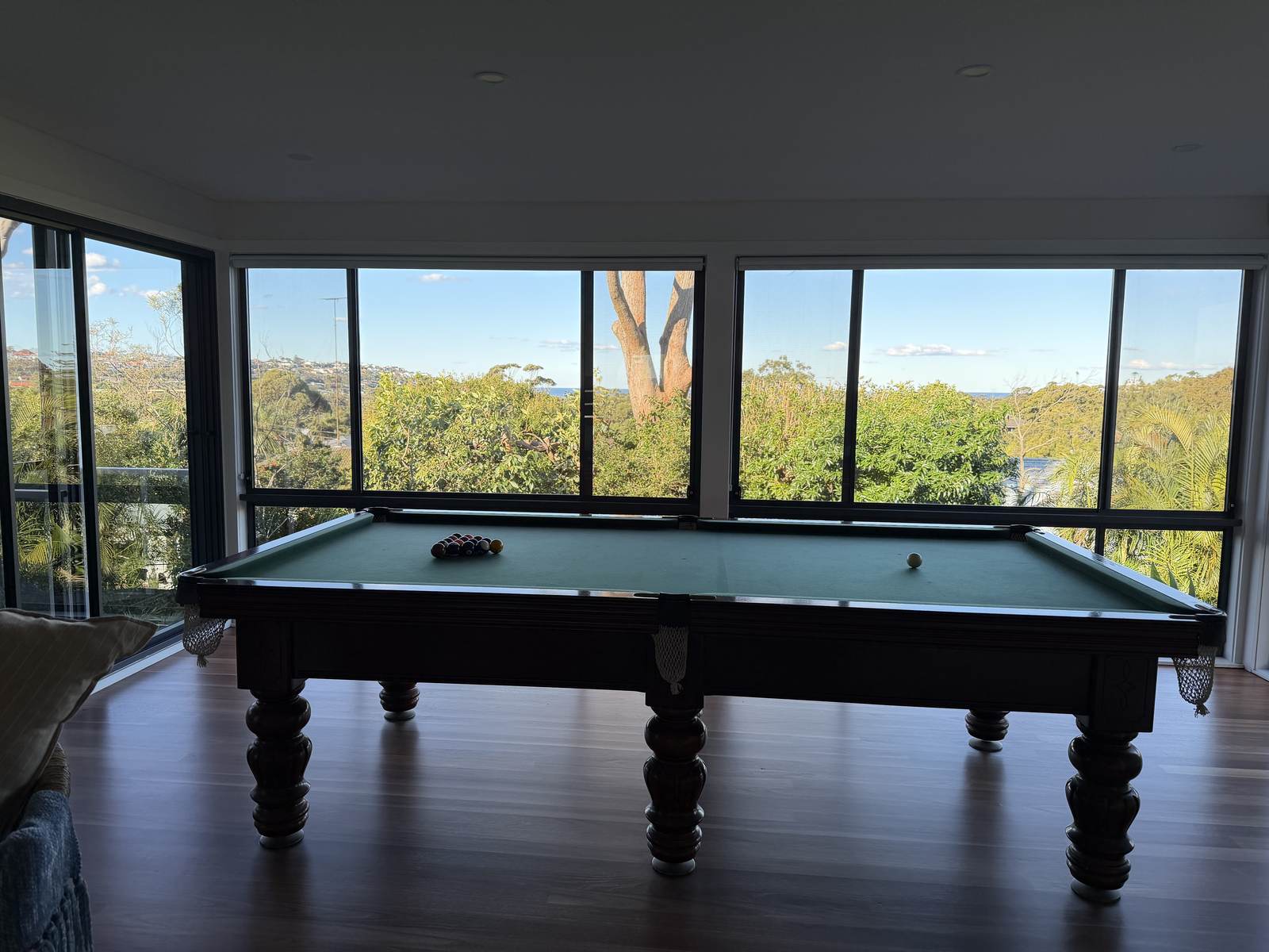 Games room with a pool table and full-height glass framing a bushland view, spotless after a clean